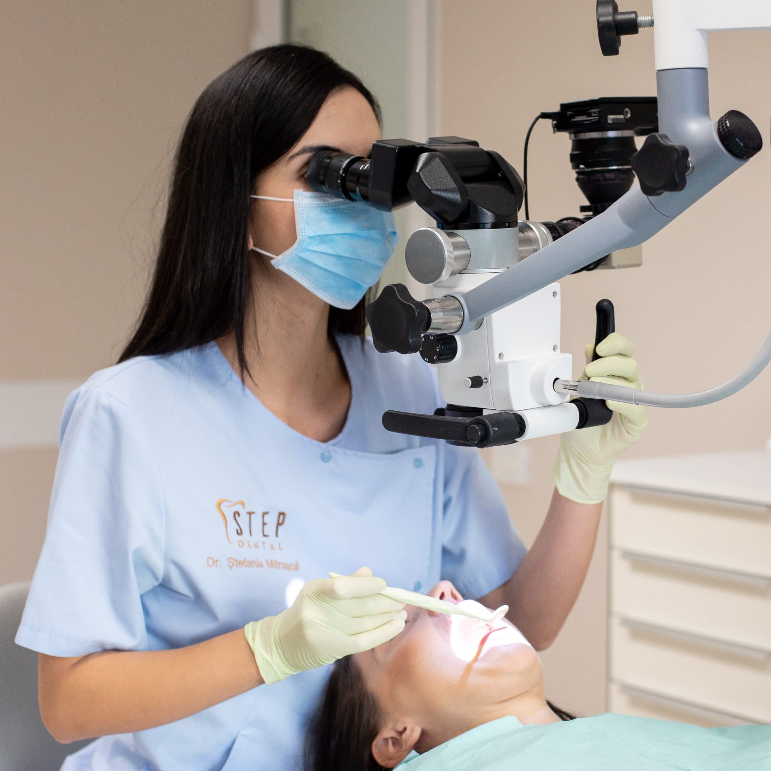 Medic Step Dental examinând o pacientă la microscopul operator